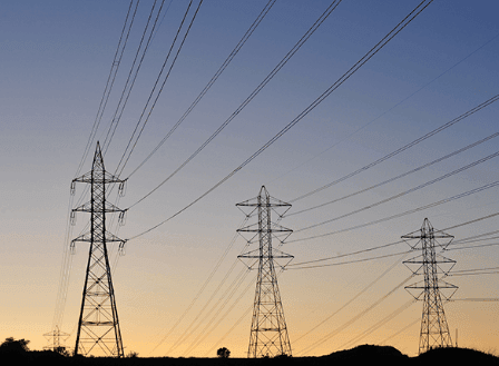Silhouette of power lines and pylons against a twilight sky.